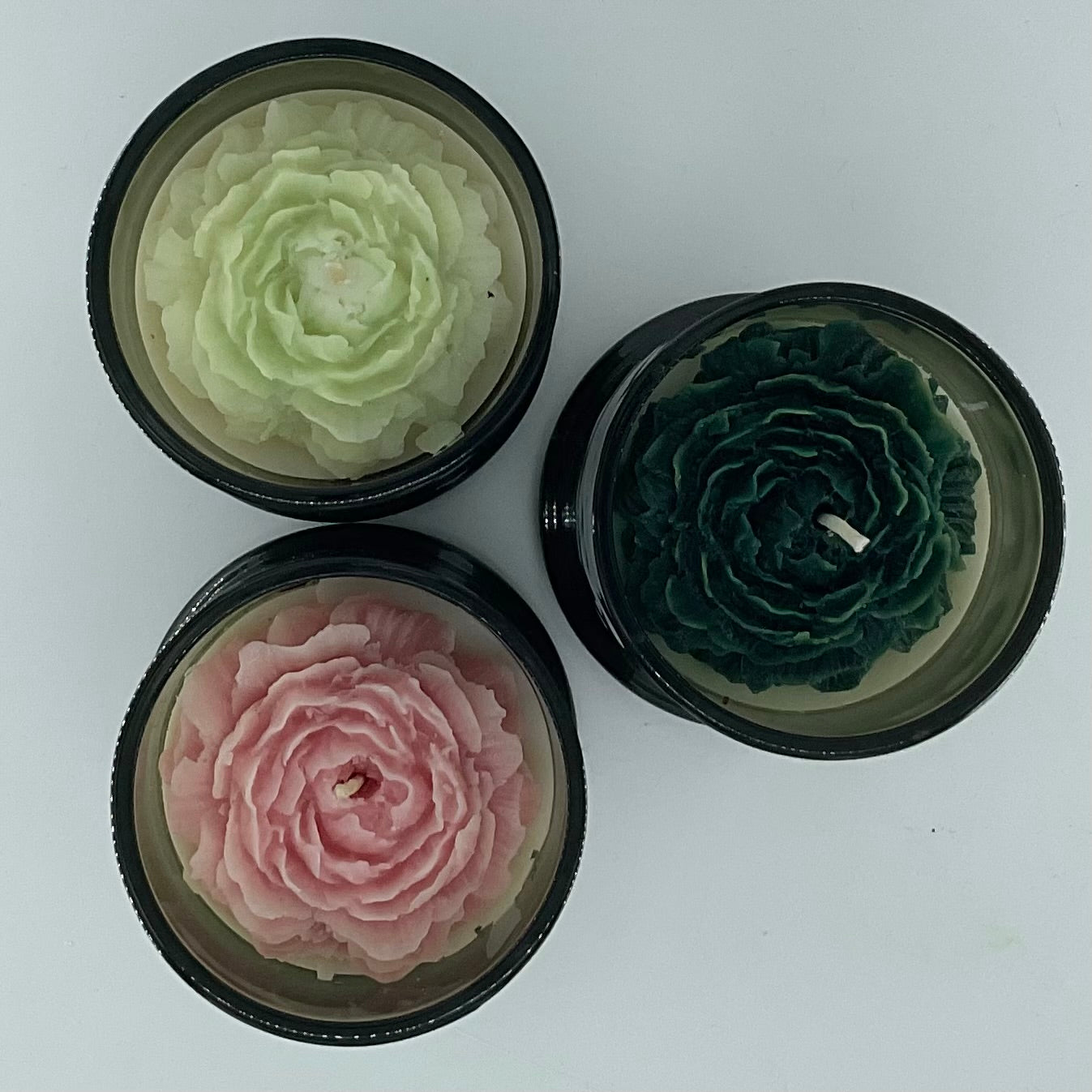 Three round containers with floral designs on a white background