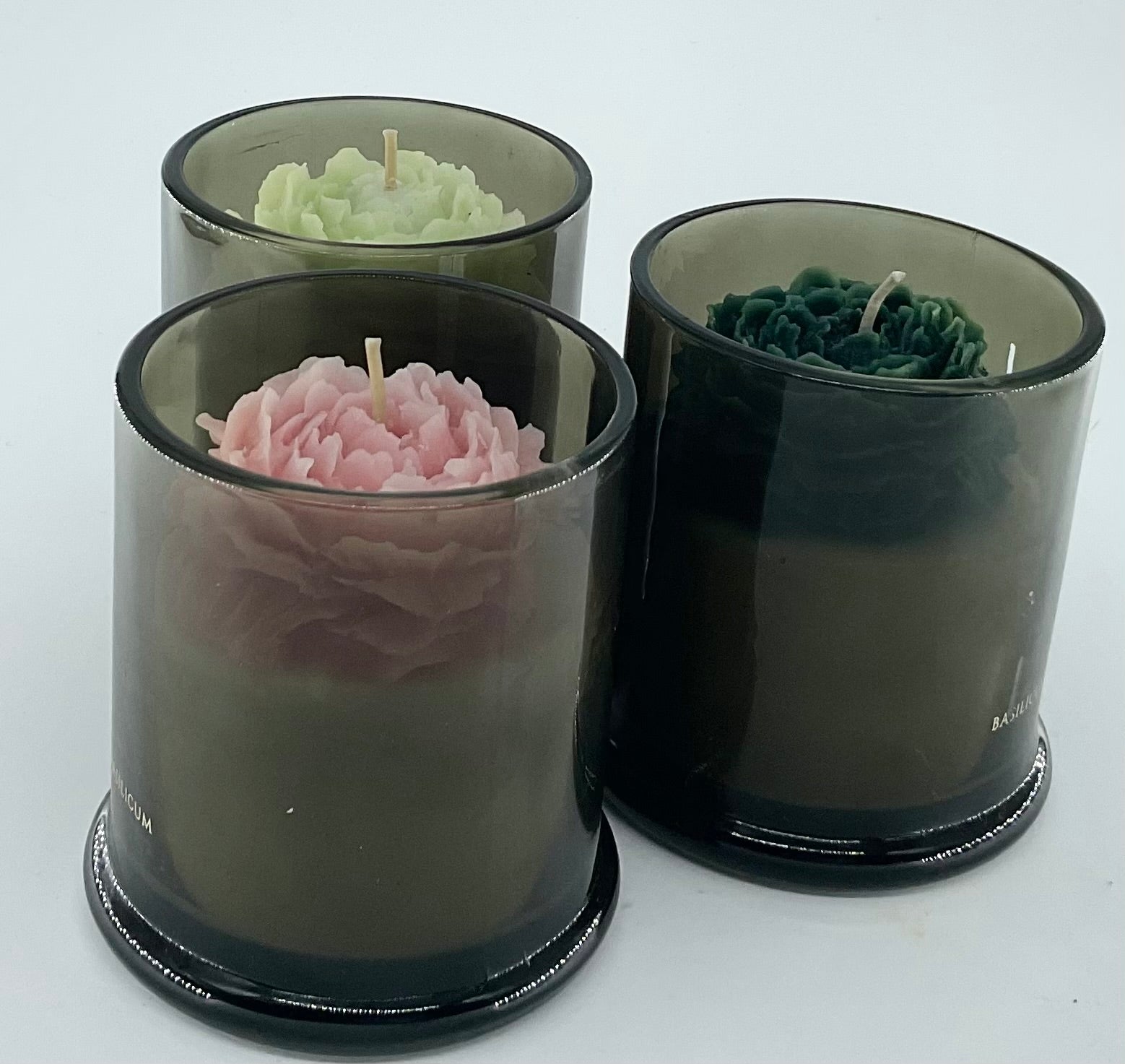 Three floral-patterned candles in clear containers on a white background