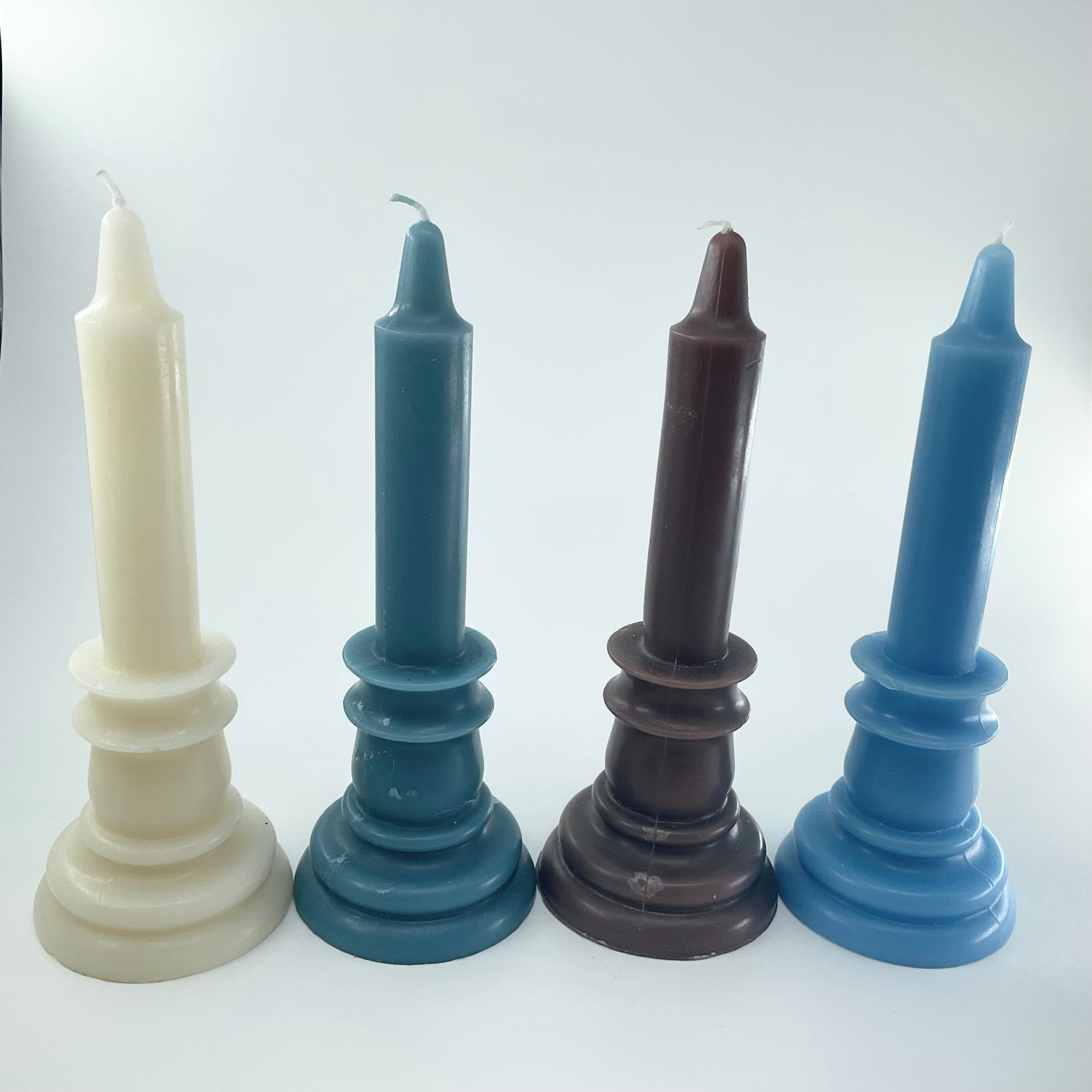 Four candlesticks in different colors on a white background