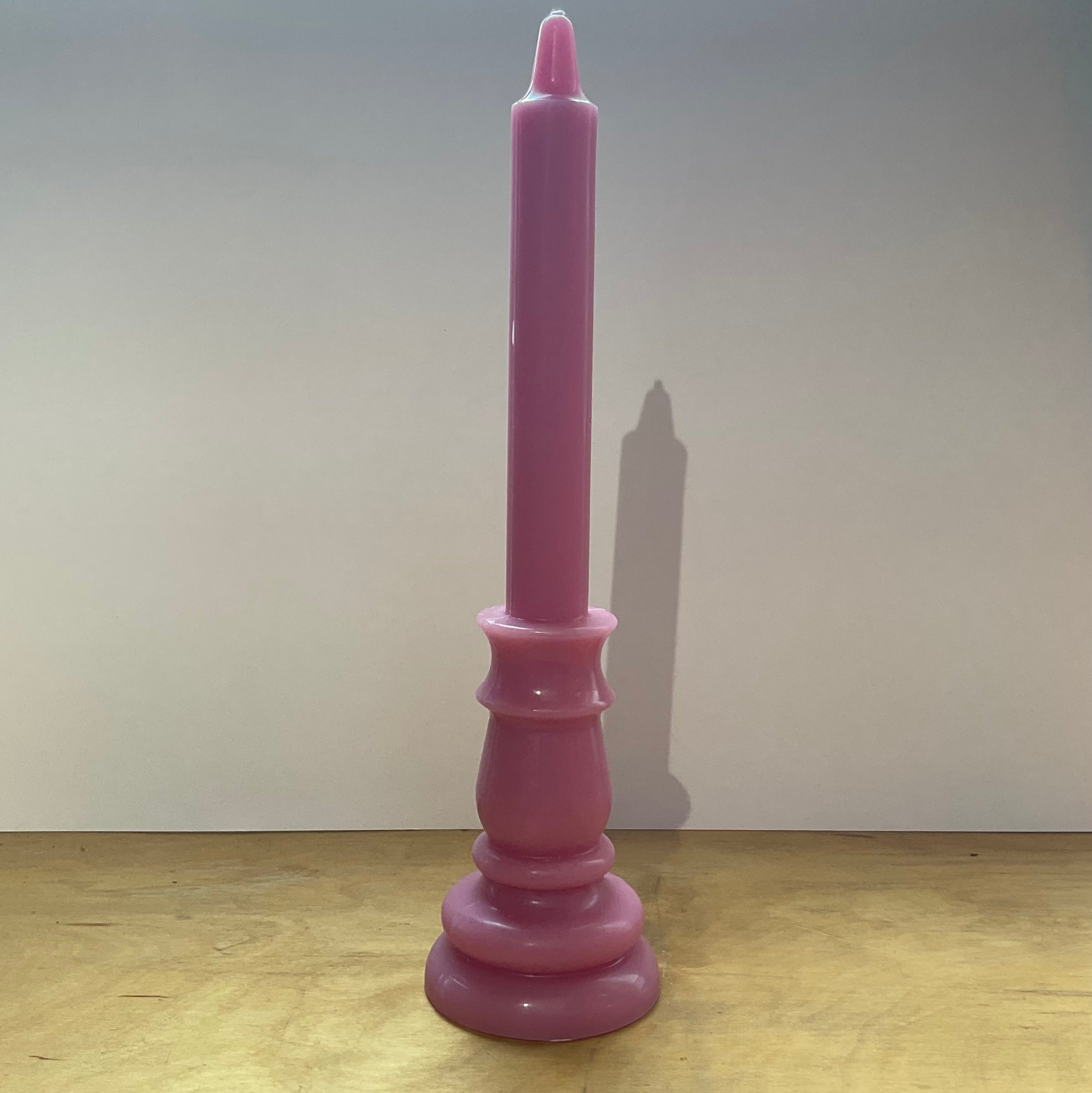 Pink candle on a pink candlestick against a white background