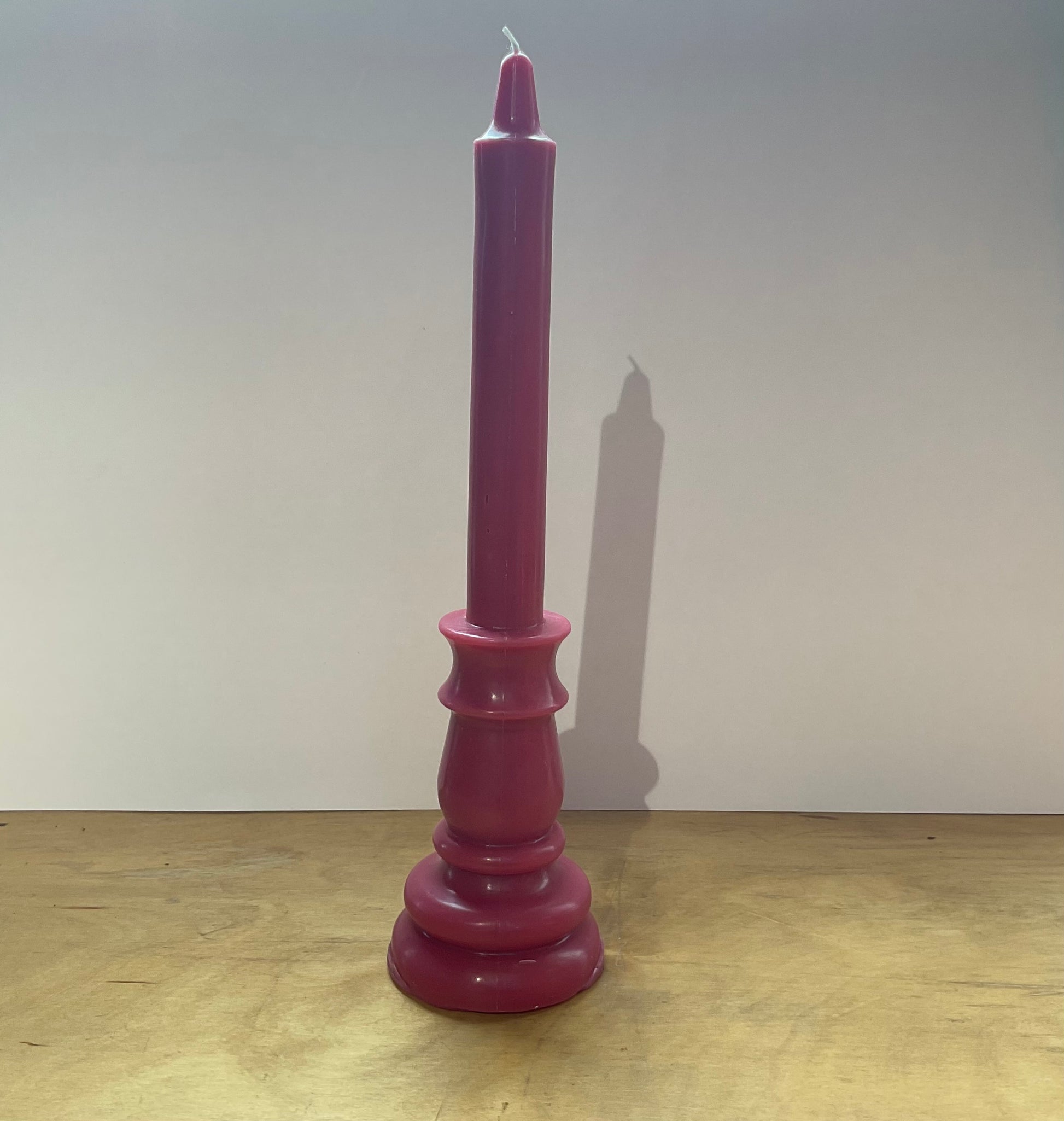 Purple candle on a wooden surface with a plain background