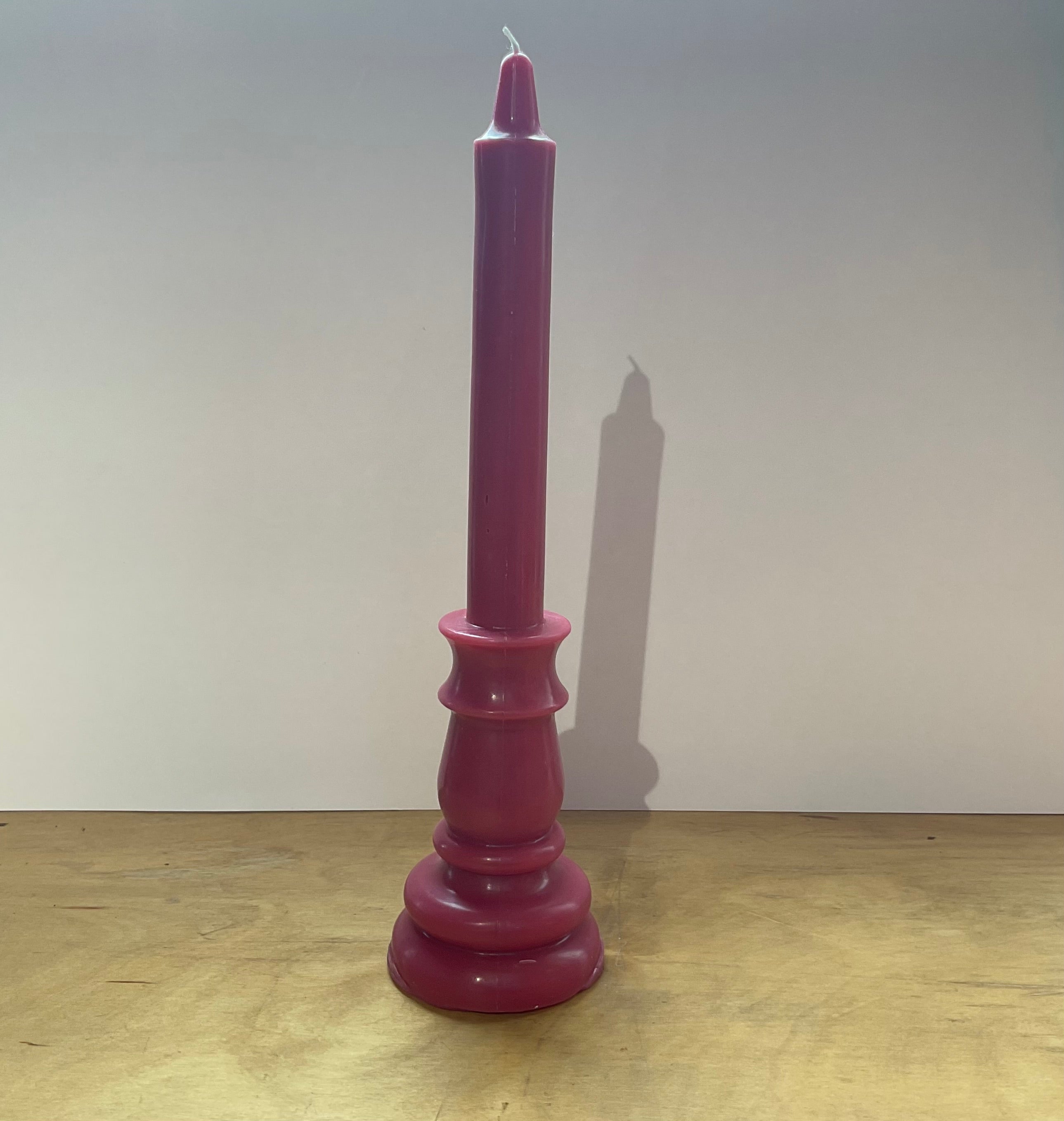 Purple candle on a wooden surface with a plain background