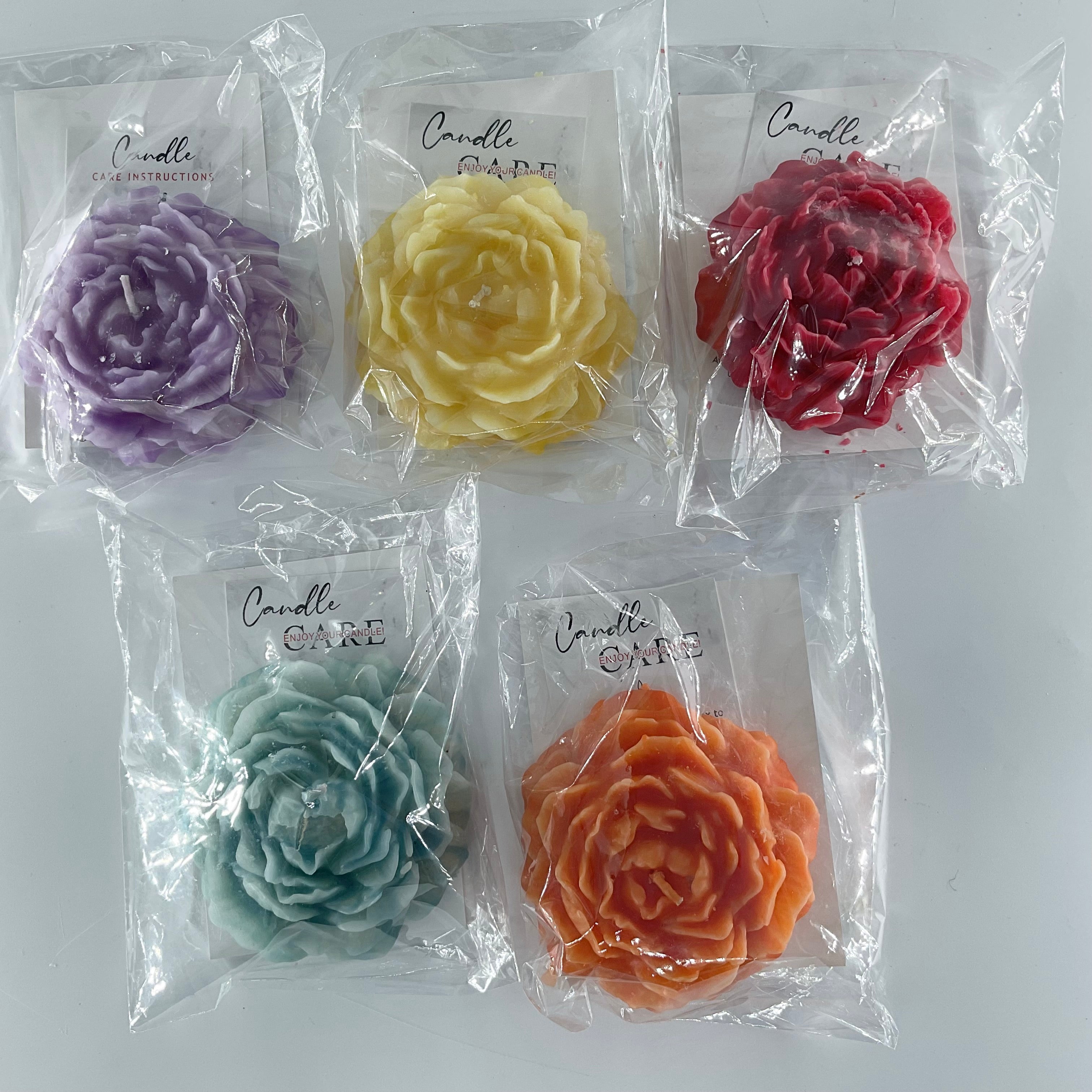 Five flower-shaped candles in different colors packaged individually on a white background.