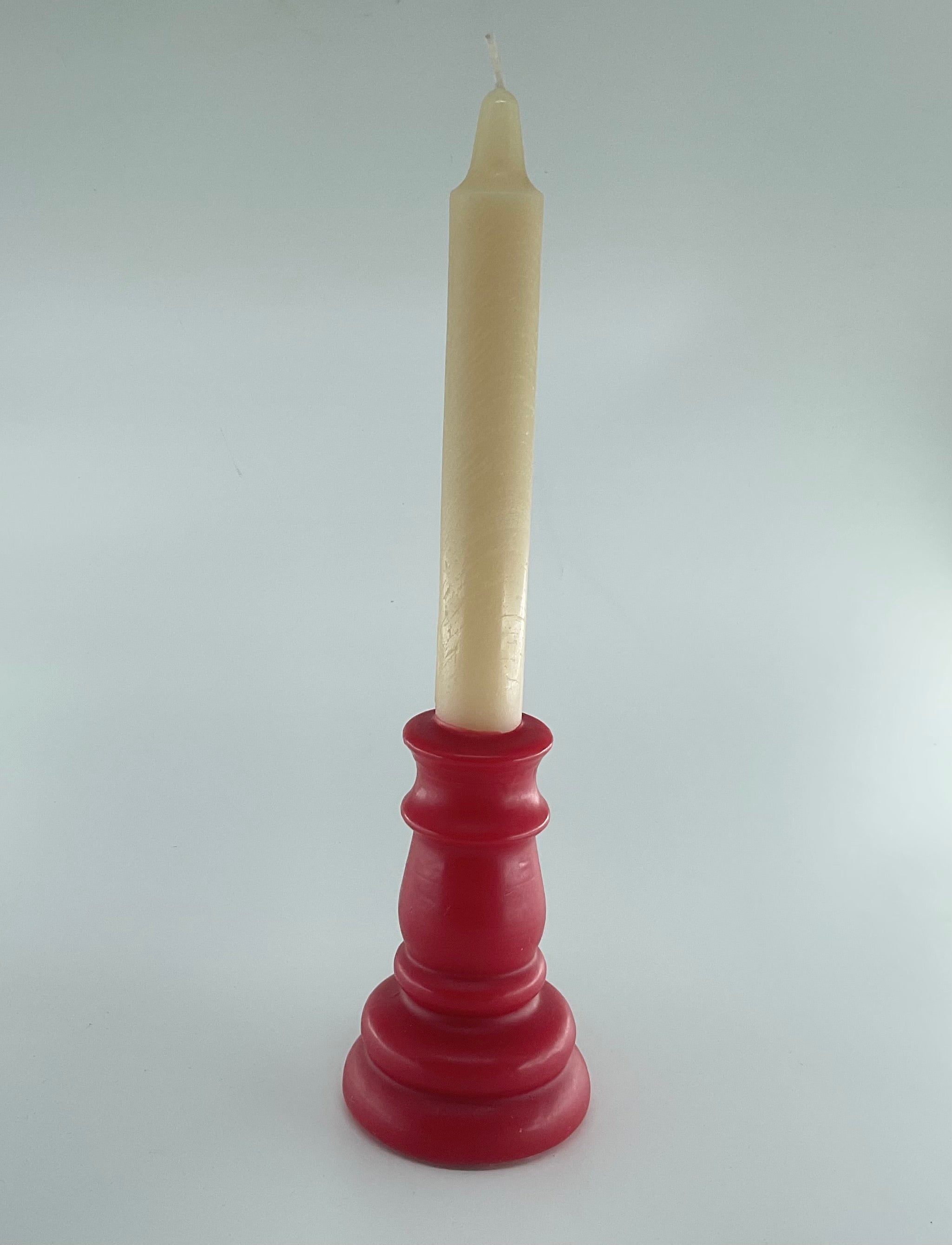 Red candle holder with a white candle on a gray background