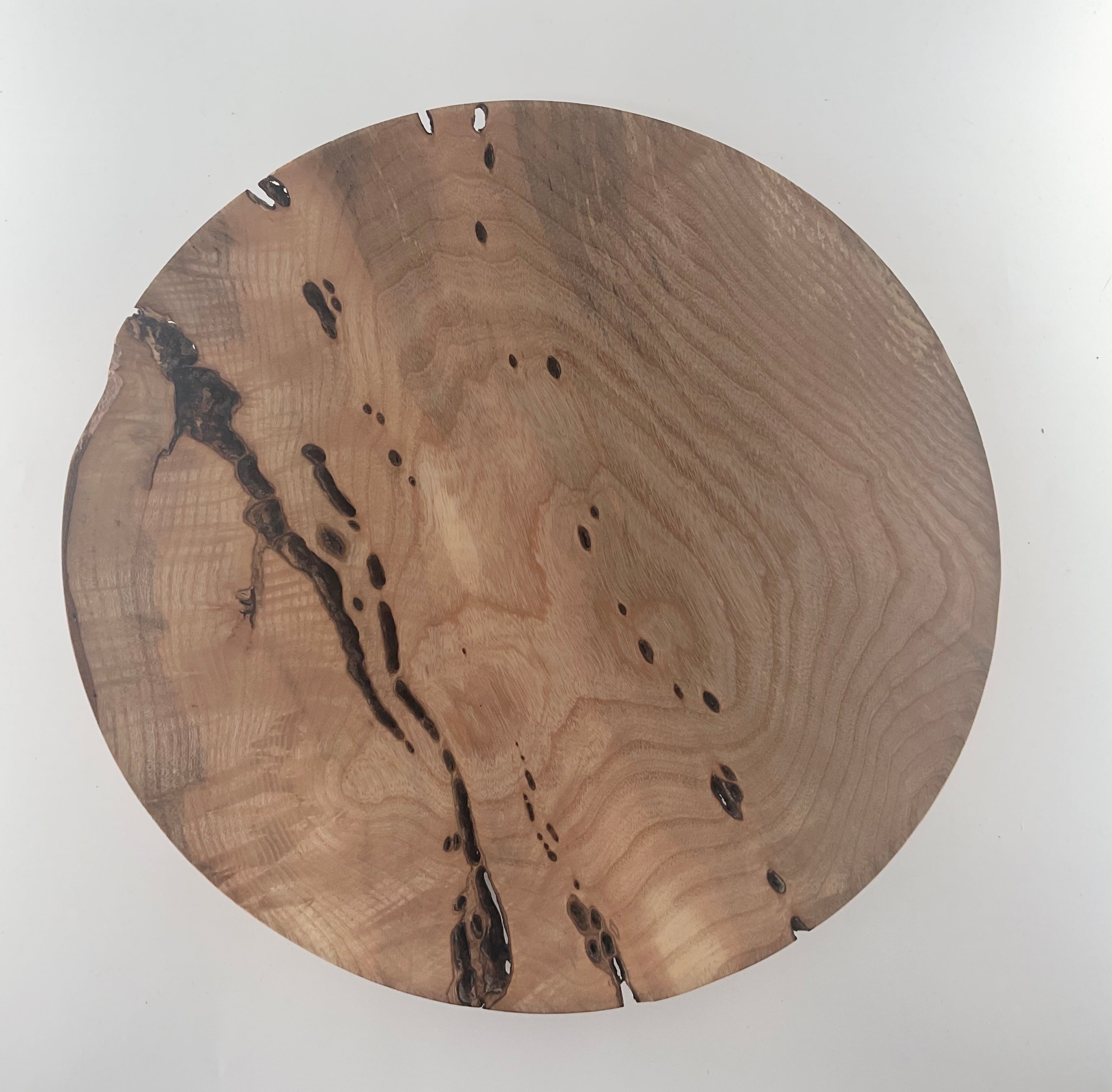 Round wooden plate with a natural edge on a white background