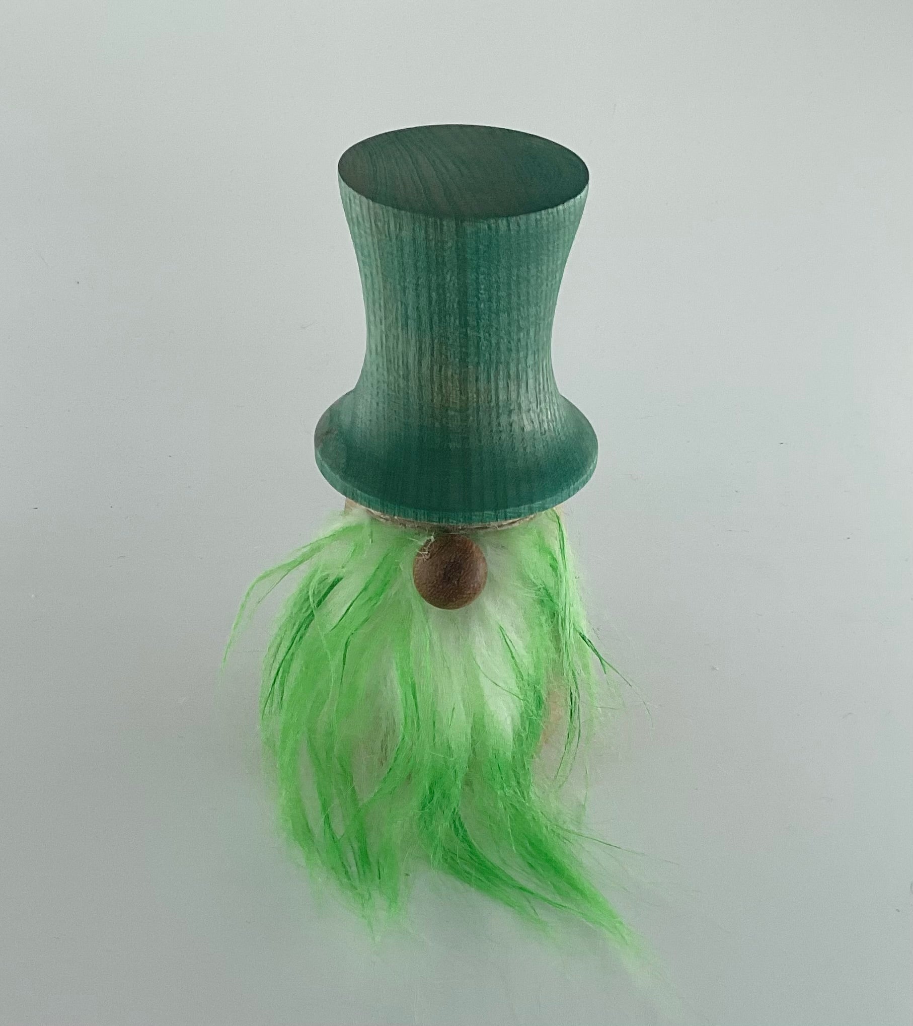 Green gnome with a brown base and bright green hair on a light gray background