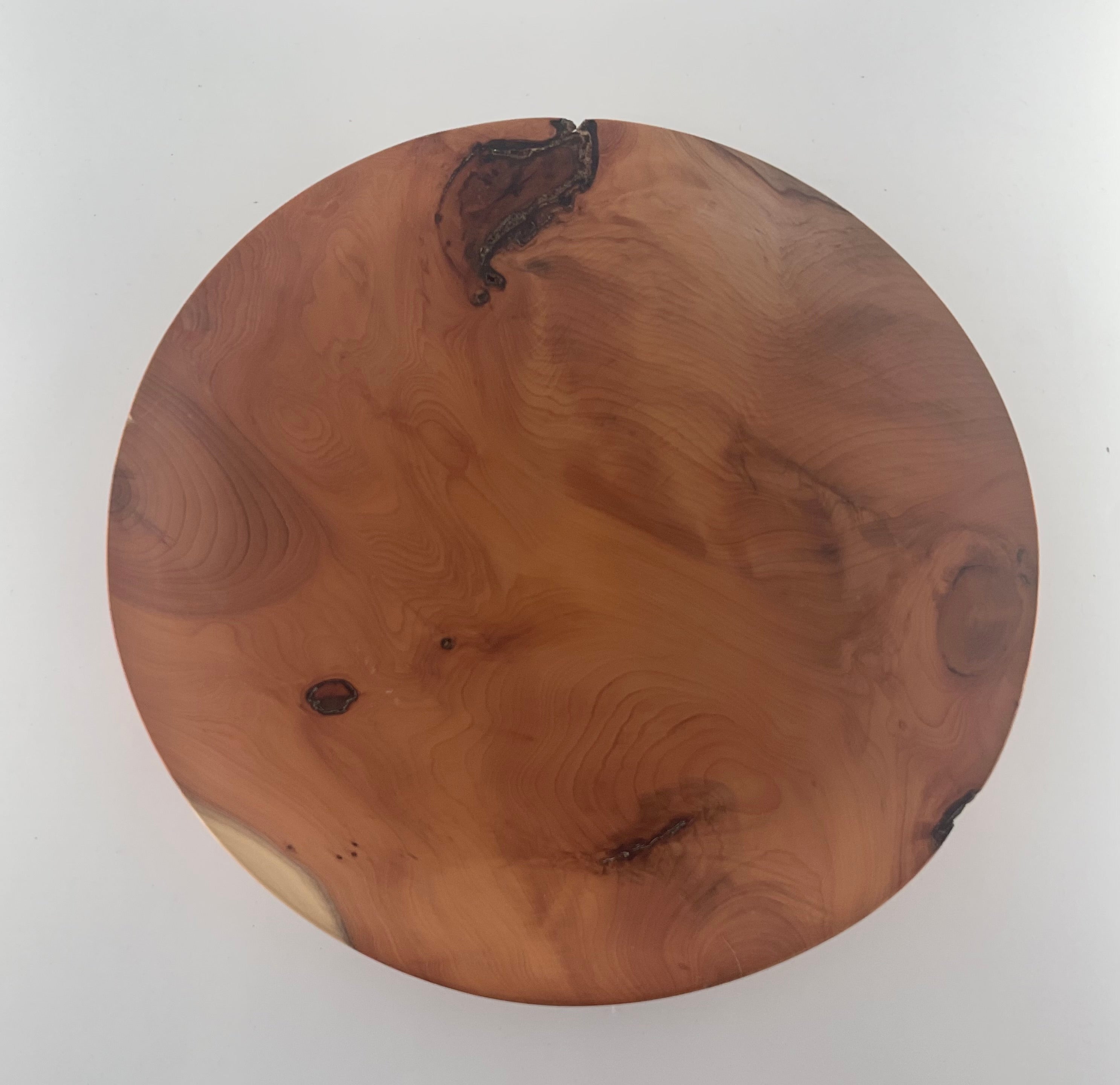 Round wooden plate with a natural grain pattern on a white background