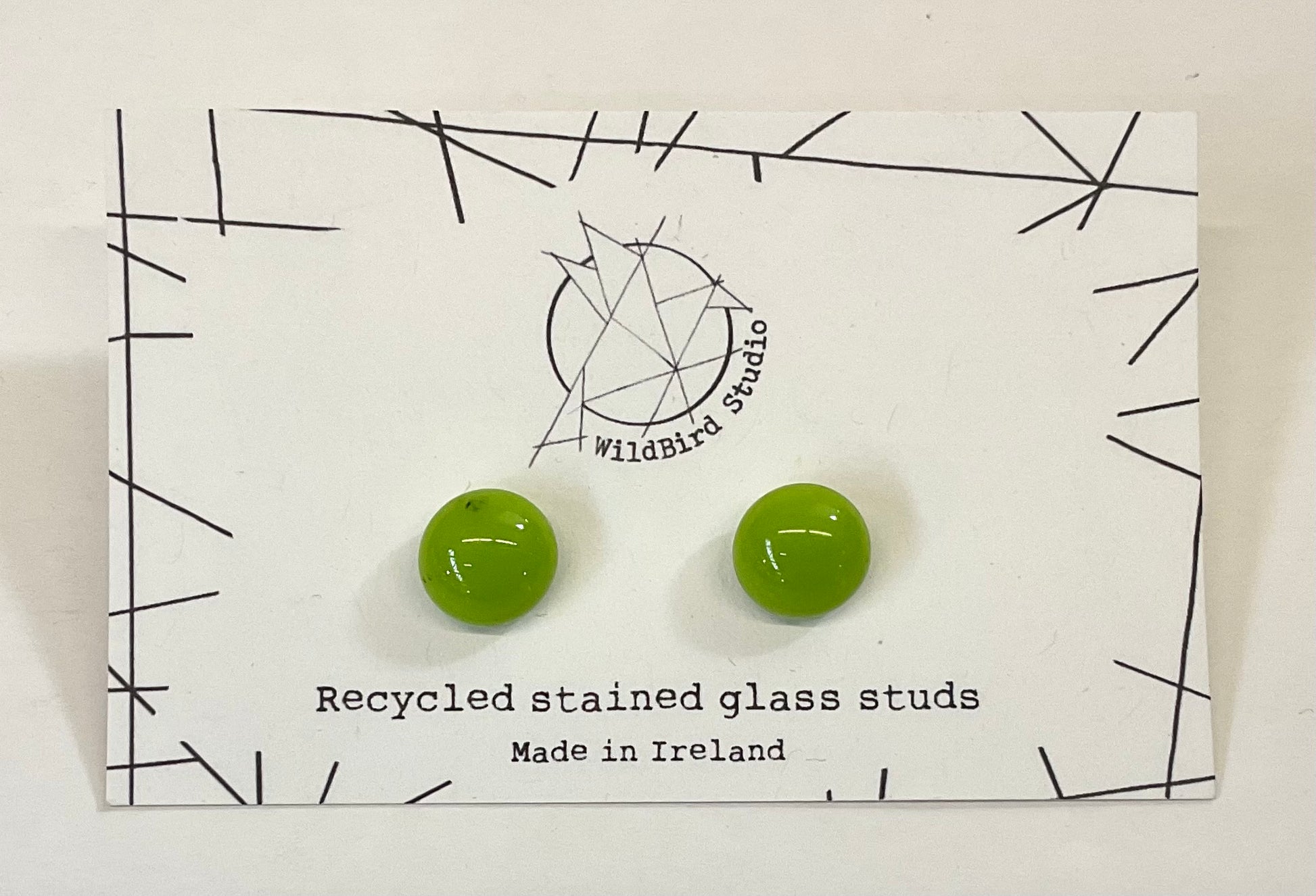 Green recycled stained glass earrings on a WildBird Studio card.