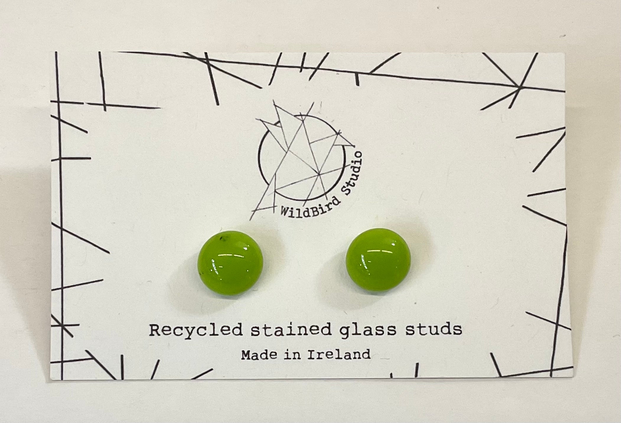 Green recycled stained glass earrings on a WildBird Studio card.