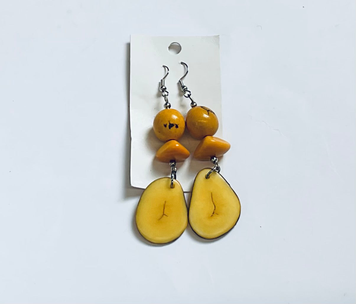 Pair of yellow fruit-shaped earrings on a white card against a light gray background