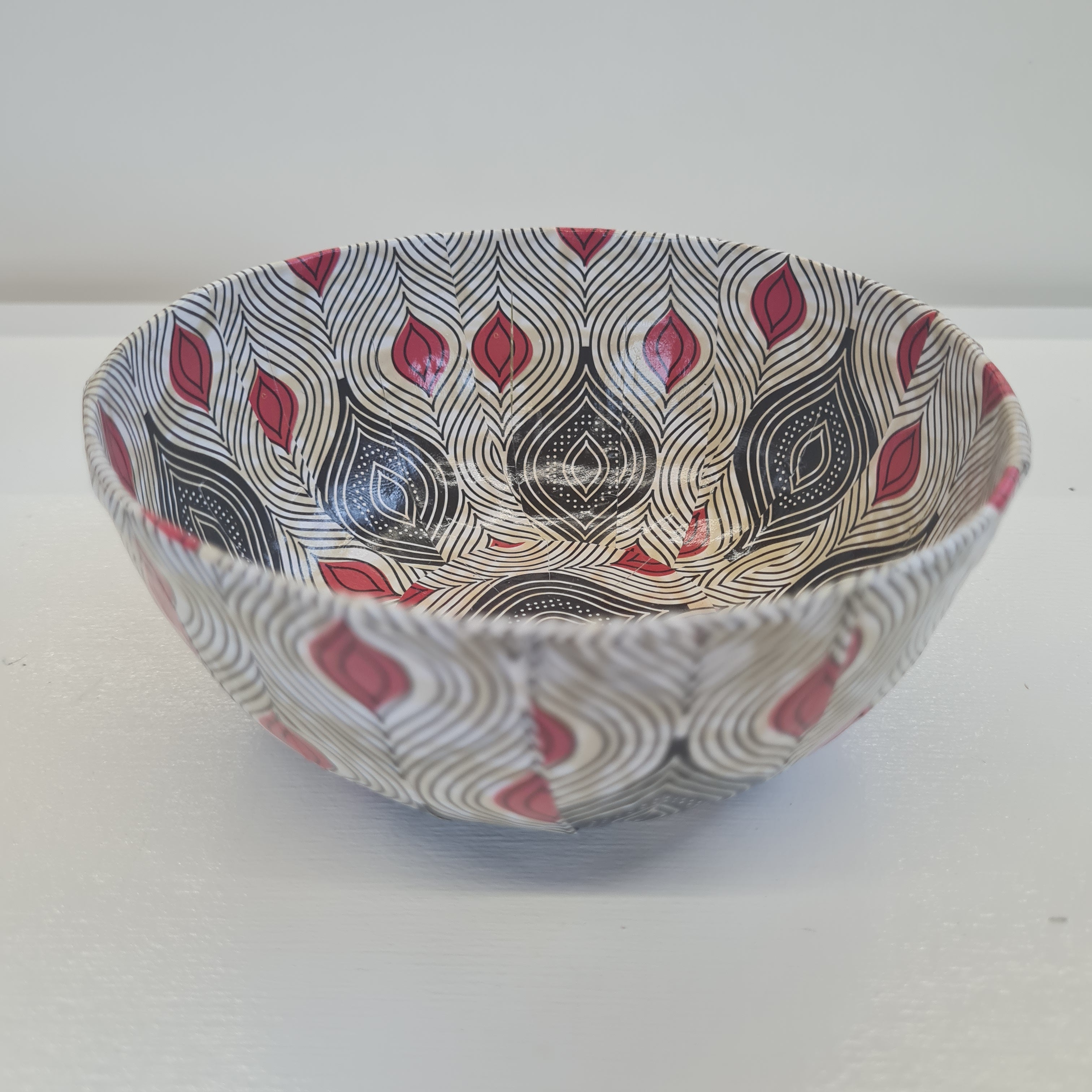 a paper ache bowl with red white and black patterns
